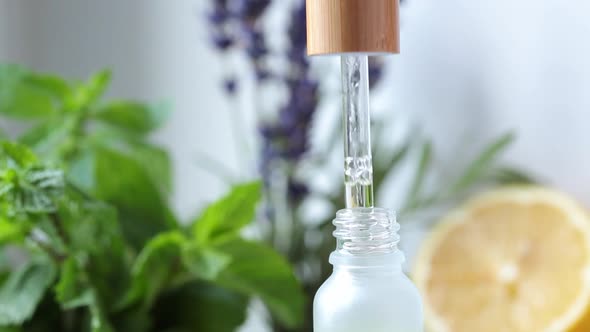 Essential oil drips from a pipette into a glass bottle. Eco cosmetics, body and hair care alt