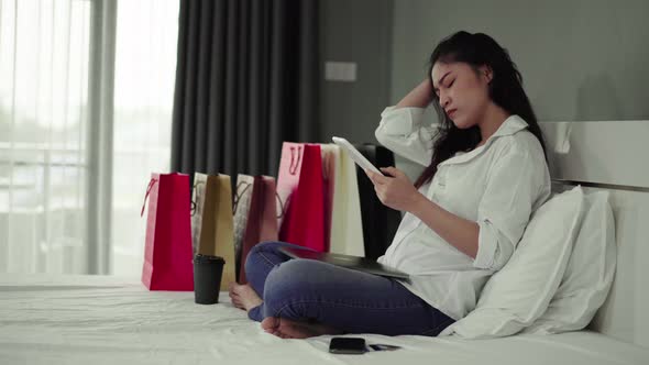 stressed woman using tablet and having problem for online shopping in the bedroom