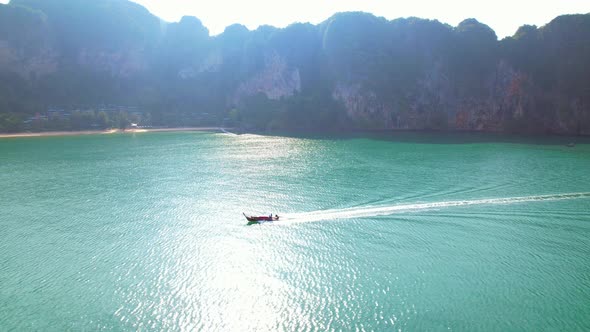 4K aerial view over a ship sailing at sea, mountains in the background. alt