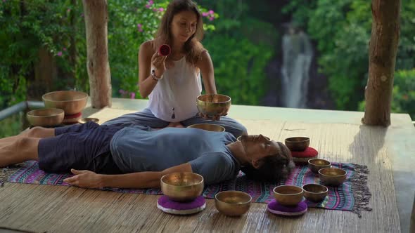 Superslowmotion Shot of a Woman Master of Asian Sacred Medicine Performs Tibetan Bowls Healing alt