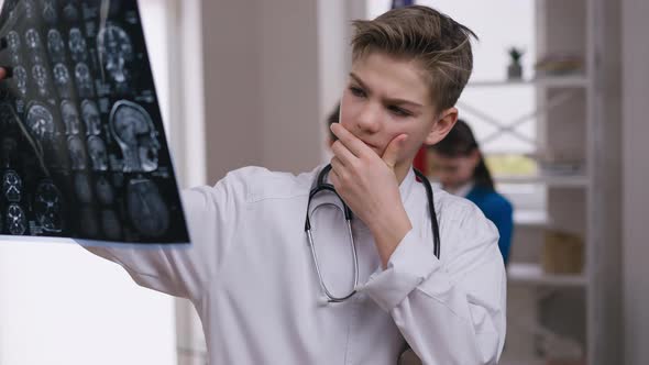 Portrait of Concentrated Little Doctor Examining Brains Xray Thinking alt