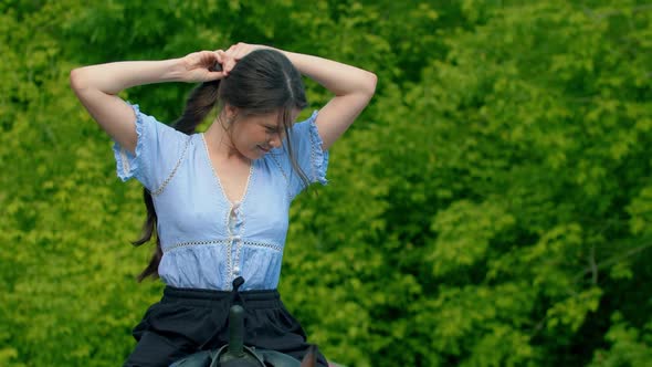 Young Smiling Woman in Blue Shirt Riding a Horse - Lets Her Hair Down alt