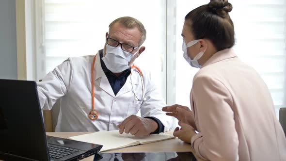 An Experienced Male Doctor Consults a Female Patient. Doctor and Patient Wearing Medical Masks alt