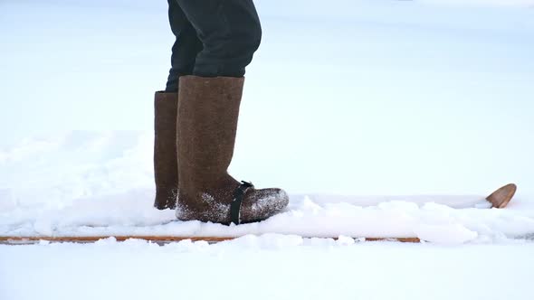 A Man in Felt Boots on Homemade Skis Walks Through the Snow Into Forest