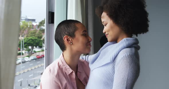 Lesbian couple romancing at window alt