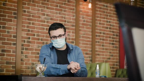 A Man in a Cafe Eats Ice Cream Without Removing the Mask From His Face.