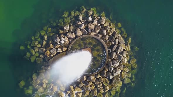 Aerial view over the Ocean Fountain with a green ocean in background and some rocks, in Paço de Arco alt