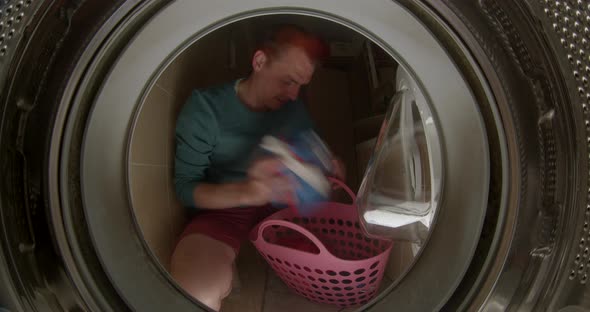 A Male Cleaner Throws Dirty Laundry Into the Washing Machine alt