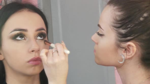 Girl Stylist Makeup Artist Applies Foundation Under the Foundation with a Special Brush on the Face alt