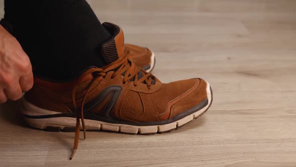 Side View of a Man's Foot in a Black Sock Wearing a Brown Leather Walking Sneaker alt