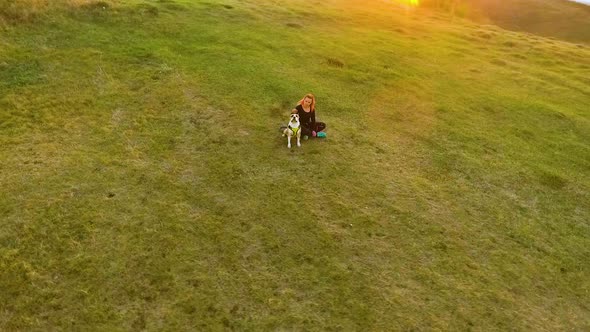 Aerial Girl Spending Time with Pet American Staffordshire Terrier on Hillside alt