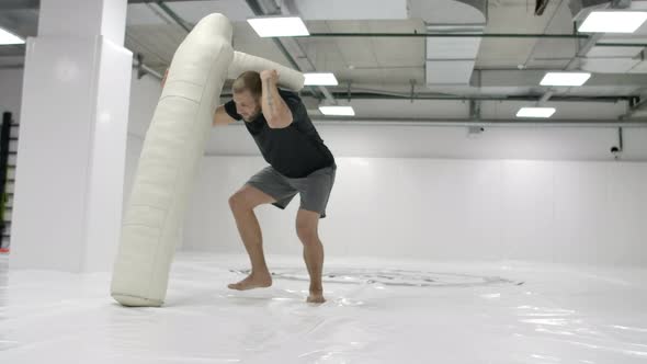 A Strong Mma Fighter is Training to Throw a Scarecrow alt