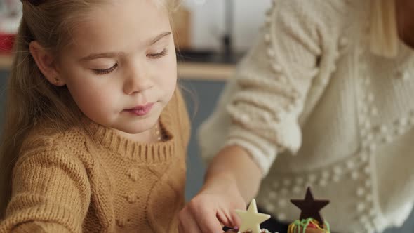 Tilt down video of family decorating together gingerbread house. Shot with RED helium camera in 8K. alt