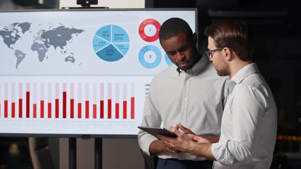 Professionals discussing corporate business statistics on the background of TV multimedia alt