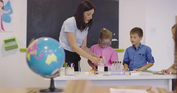 Elementary School Science Classroom Enthusiastic Teacher Explains Chemistry to Diverse Group of alt
