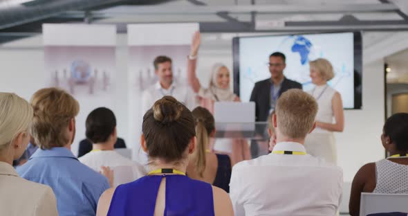 Female speaker and applauding audience and colleagues at a business conference alt