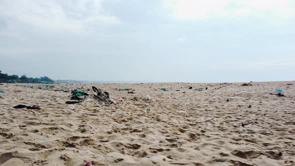 Low aerial flying over beach sand with garbage, Vietnam alt