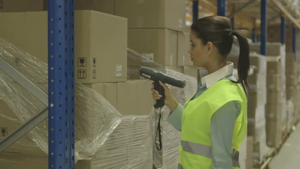 MS Young woman using a scanner to scan boxes in factory