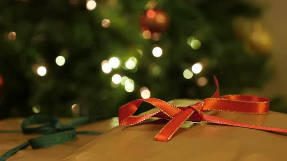 Christmas gift wrapped in golden paper close-up 4K 2160p 30fps UltraHD footage -  Shiny red ribbon a alt