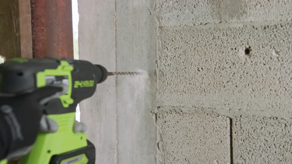 Man drilling hole in concrete wall. Repair works indoors in slow motion alt