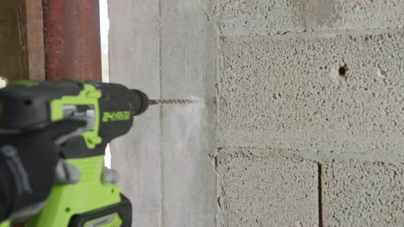 Man drilling hole in concrete wall. Repair works indoors in slow motion