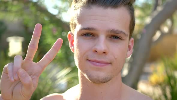 A fit young attractive white man giving the peace sign and prayer hands as he meditates on positivit alt