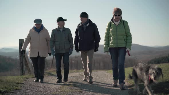 Four Retirees Walking on Path in Rural Landscape