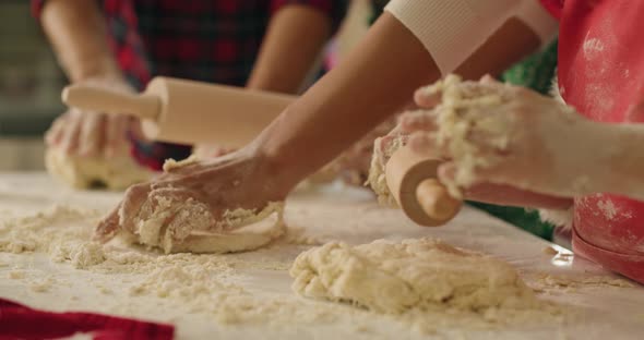 Handheld view of family rolling the dough for Christmas cookies alt