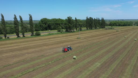 A Round Baler Discharges a Fresh Wheat Bale During Harvesting alt