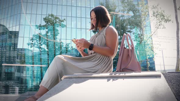 Business woman working in the courtyard surrounded by high-rise office buildings with glass facade o alt