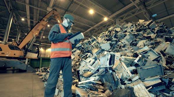 Dumpsite Inspector with a Tablet Observing a Pile of Waste alt