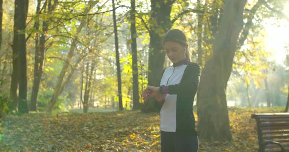 Sportswoman Using Smart Watch and Listening To Music During Morning Training. alt