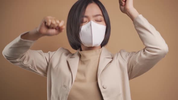 Close up shot of Asian business woman wearing hygienic mask and dancing isolated