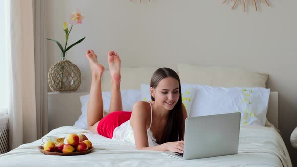 Girl Lying In Bed With Laptop, Checking Mail And Typing Message