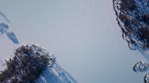 Aerial birdseye view of snowy bog landscape with frozen lakes in sunny winter day, Dunika peat bog ( alt