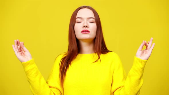 Middle Shot of Slim Cute Redhead Woman Meditating at Yellow Background alt