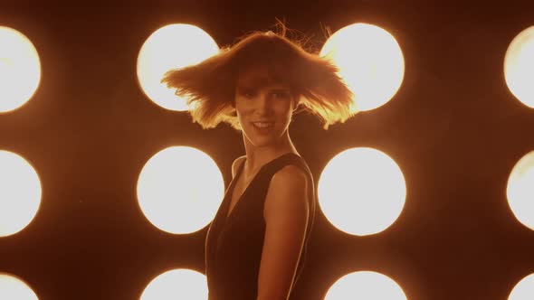 Beautiful woman dancing in front of a wall of lights alt