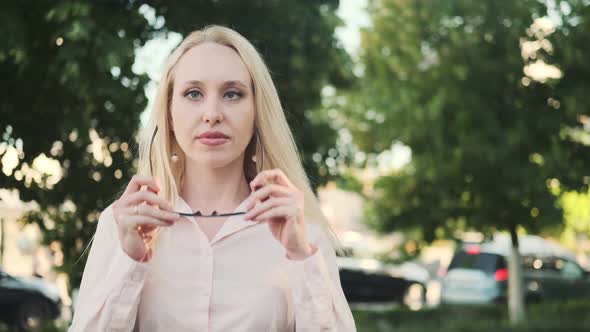 Beautiful girl in a shirt with an incorrect position of the eyes (strabismus) puts on glasses, smile alt