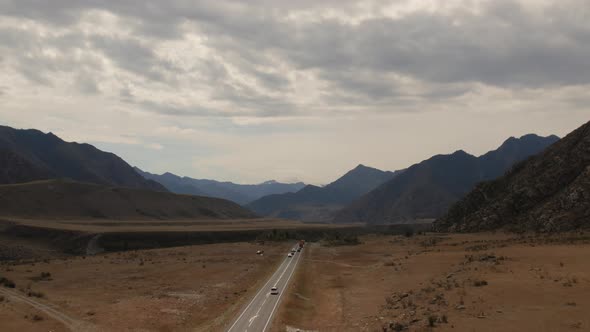 Mountains valley of Altai with traffic cars on Chuya highway under dramatic sky
