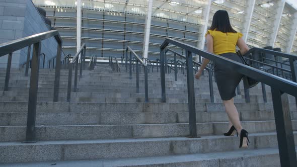 Business Woman Walking Up Stairs To Office Center alt