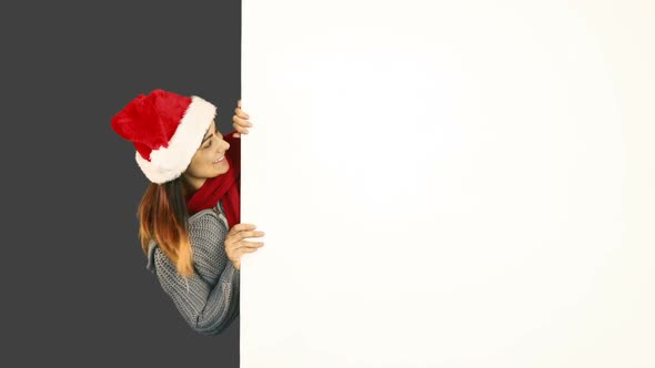 Beauty brunette in santa hat pointing white poster alt