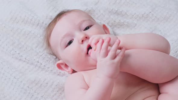 Portrait of a happy infant baby on the bed pulling his leg into his mouth, eight months old