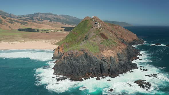 Cinematic Aerial View of a Lighthouse on a Scenic Green Rocky Island, Summer  alt