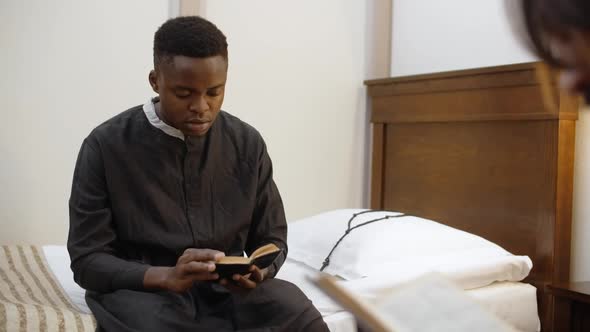 African American Young Catholic Priest Reads the Bible at His Room Seminarist is Reading a Book