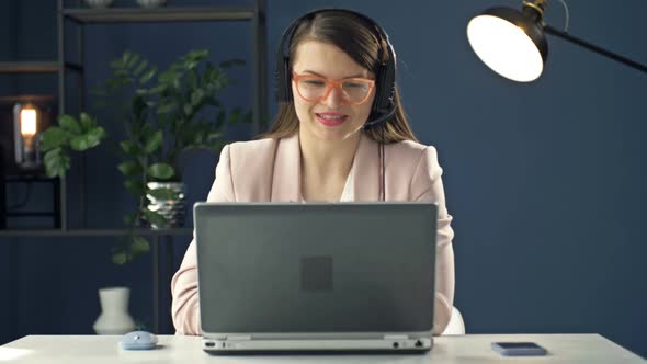 Portrait of a Young Woman in a Headset Working at a Laptop