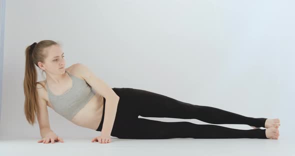 Slender Girl Does Exercises Lying on Her Side and Lifting Her Leg Up alt