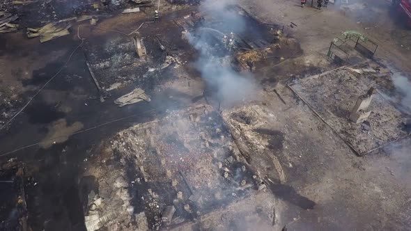 Aerial View Over Smouldering Ruins in Smoke, Firefighters Are Extinguishing Fire