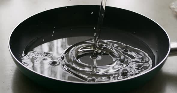 Close-up. A drop of water falls into the pan. Slow motion
