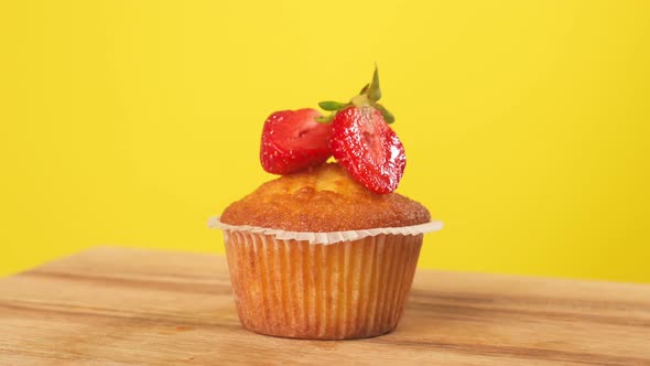 Baking a Cupcake with Strawberries Rotates on a Yellow Background
