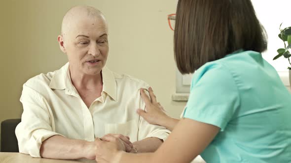 Female Oncologist is Trying to Cheer Up an Elderly Woman with Cancer alt